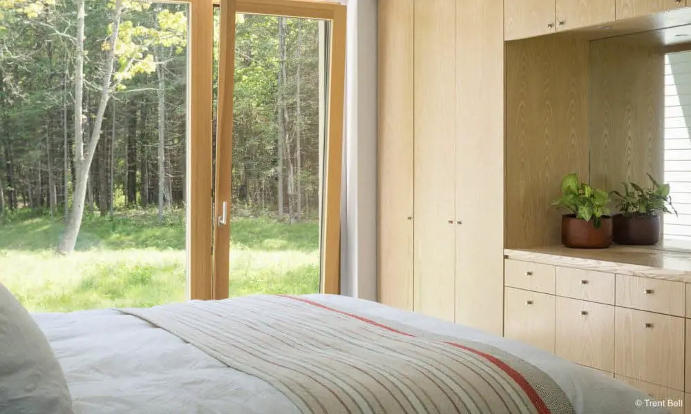 Go Home 1700 sq ft by Go Logic prefab home master bedroom with view through large window and terrace door.